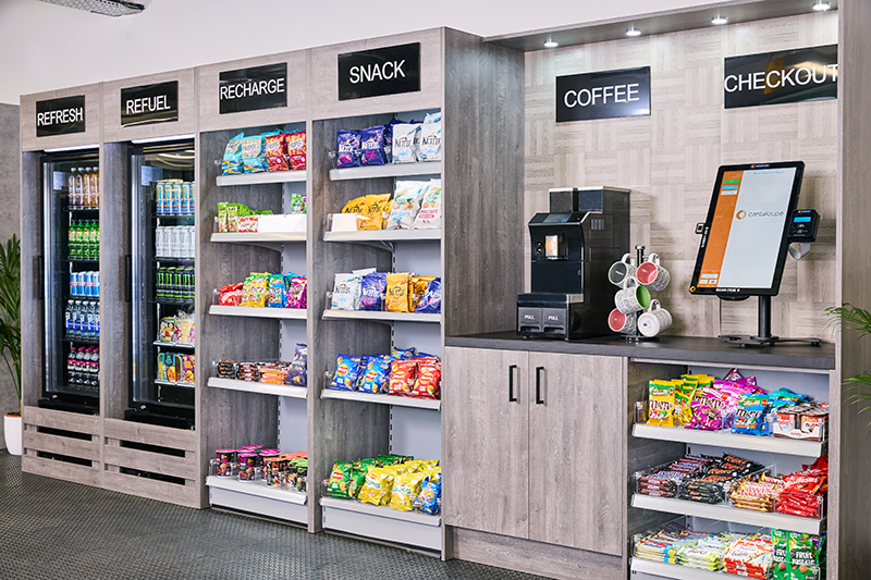Open micro market wall with shelving and coolers in a workplace break area