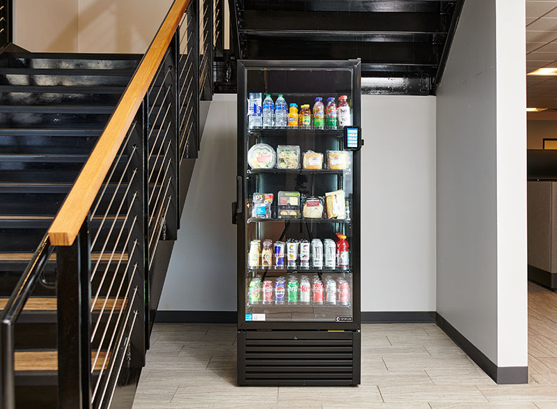 Smart cooler with a glass front stocked with drinks and snacks in an Atlanta office